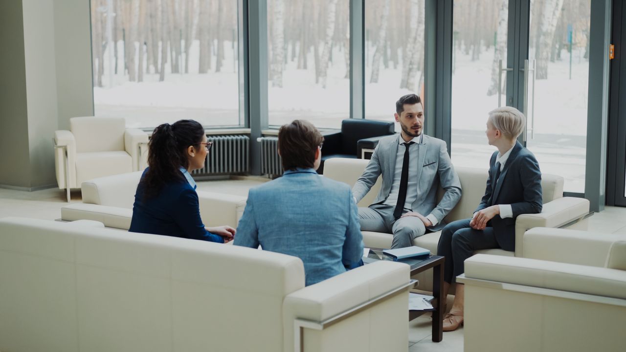 Group of professionals having a discussion in a bright office lounge.